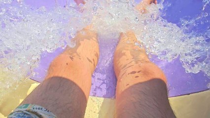 Boy goes down a waterslide and collides with a man in his way