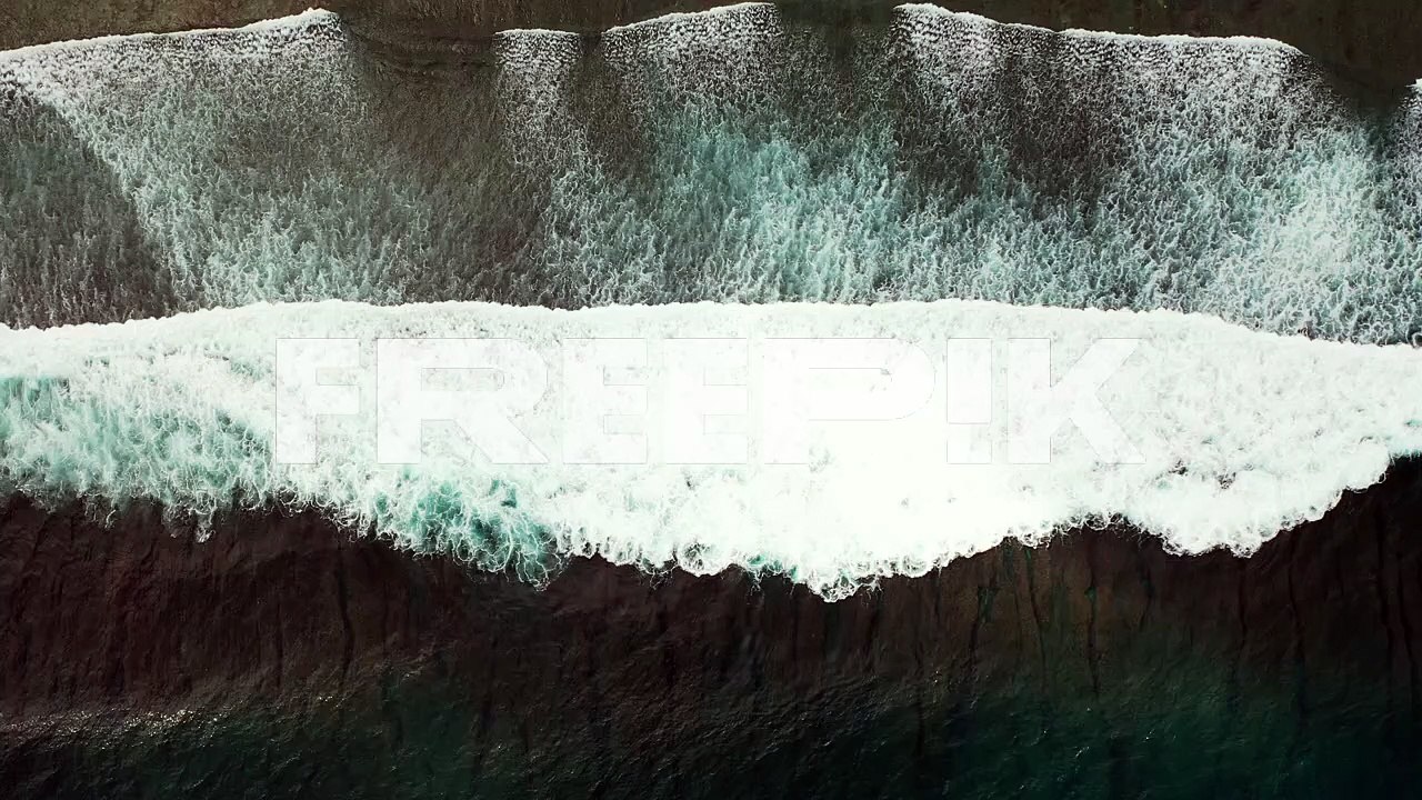 Aerial of a small white wave breaking and crashing in the middle of the dark blue ocean