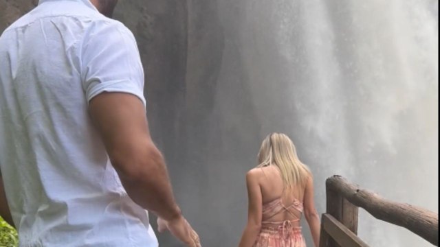 Surprise marriage proposal catches woman off guard while she admires a breathtaking waterfall scene