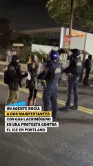 Un agente rocía gas lacrimógeno en la cara de dos manifestantes en Portland