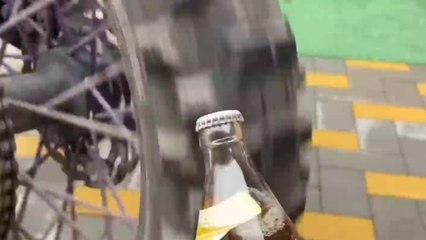 Lad uses enduro motorcycle's spinning wheel to open a bottle
