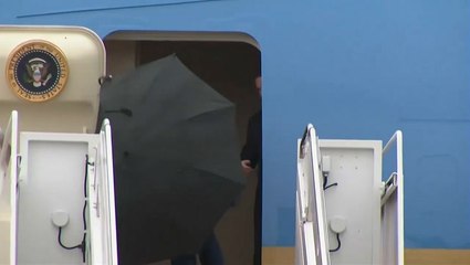 Trump struggles to take down umbrella during storm as he heads to Middle East