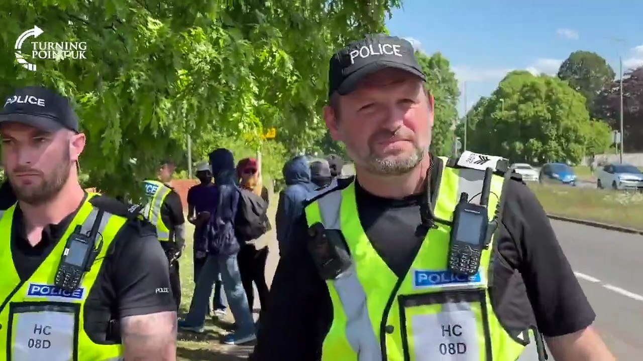 Hampshire Constabulary escort masked ANTIFA thugs past a local-led migrant..