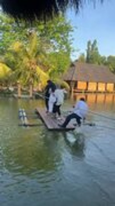 Man Nearly Falls Into Fish Pond While Pushing Wooden Plank