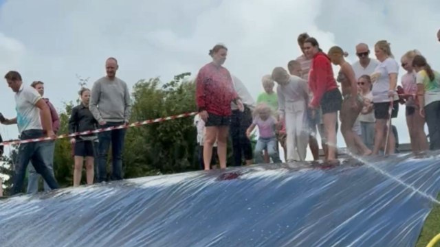 Little girl slowly navigating a water slide gets hilariously knocked over by kids behind her