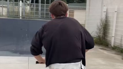 Lad tries a trick with his hand roller scooter at a skatepark and falls