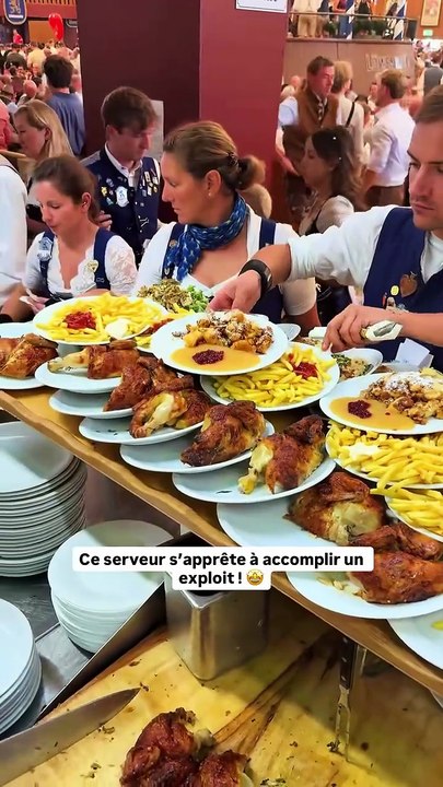 À l’Oktoberfest à Munich, le serveur relève le défi avec brio : une immense planche chargée d’assiettes prête à défier la gravité. 🍺💪
