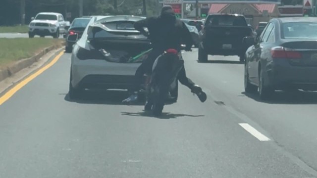 Footage of dirt bike rider falling off after suddenly losing control while doing a bizarre stunt with a car
