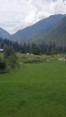 The natural beauty of Halmat in the Neelum Valley is enhanced by dark clouds, light rain, and green mountains.