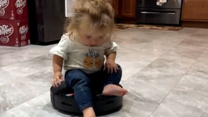 Little girl decides to ride the robot vacuum with a big smile