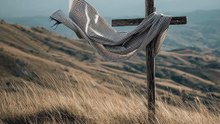 Cross on a hillside with a shawl on it blowing