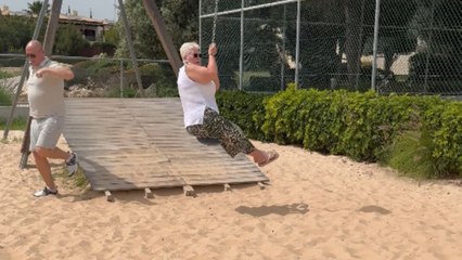 Granny attempts a zip-line ride and takes a comical fall straight into the sand below