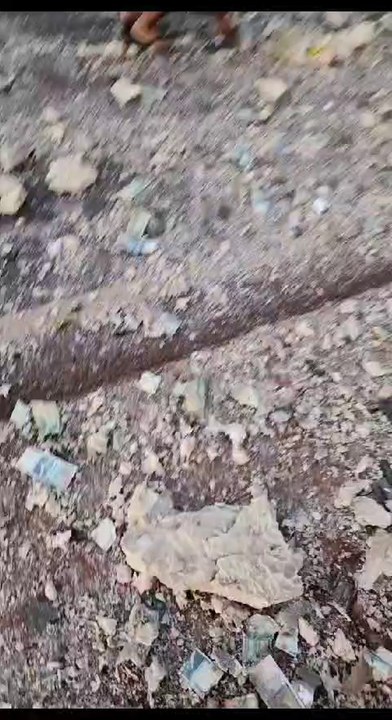 Gente juntando billetes del transportador de caudales de Prosegur reventado durante asalto en Itaipúa