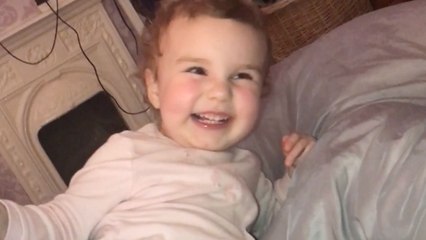 Little girl plays on bed and laughs while trumping on demand
