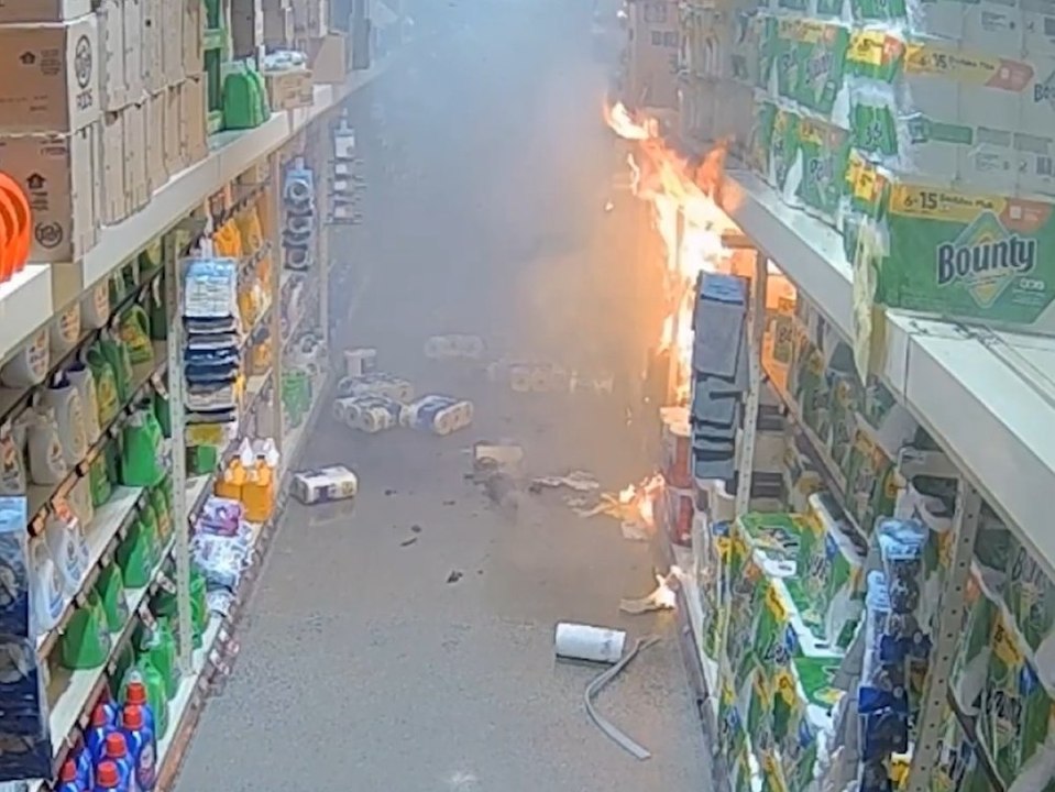 Mitarbeiter zündet Regal mit Papierprodukten im Supermarkt an