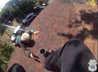 Elderly man dangling from three-story building after slipping while blowing leaves off his roof is rescued by cops