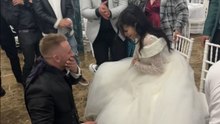 Wedding guest kisses groom while he removes garter from bride’s thigh