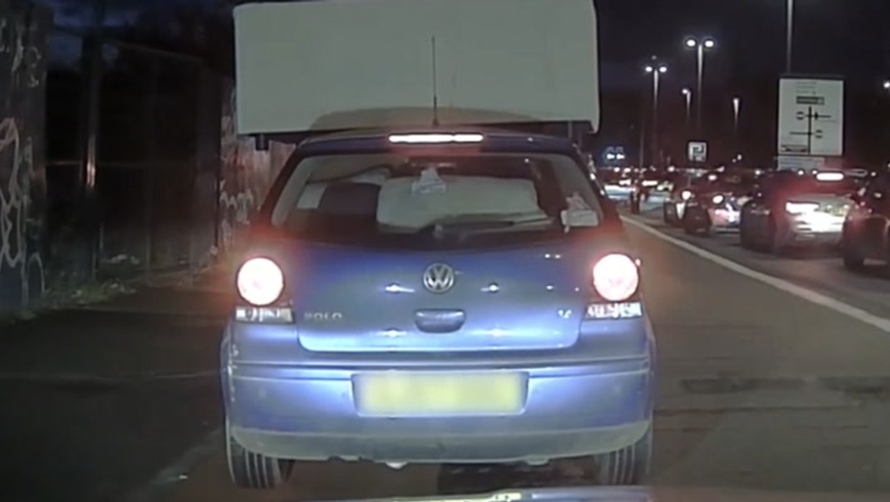 Passenger clings to sofa balancing precariously on car’s roof