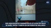 Dos adolescentes caminan bajo la lluvia en traje de baño, patos y careta en un pueblo de Mallorca
