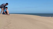 Boy tries a steep slope while sandboarding but loses balance and flips over