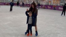 Woman guides her son on skates and tries not to let him fall