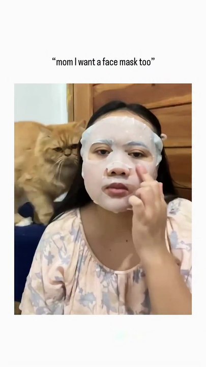 The video captures a woman applying sheet face masks to herself and her two orange tabby cats_a mother and kitten_creating a whimsical family self-care mome(