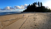 Queensland man carving sand with a rake to create beach art every day