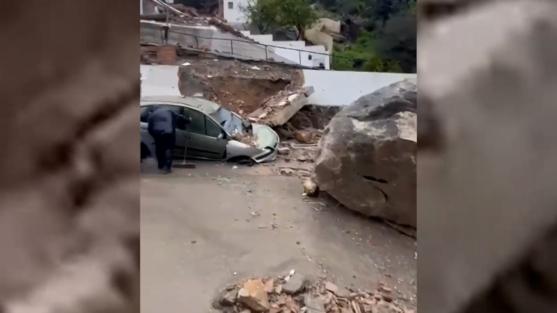 La localidad gaditana de Ubrique ha vivido este mi�rcoles una jornada de m�xima tensi�n tras un grave incidente geol�gico que ha estado a punto de terminar en tragedia. Minutos antes de las 13:00 horas, un desprendimiento de una roca de gran tama�o desde la ladera de la monta�a ha impactado directamente contra una zona residencial situada a los pies del monte. El suceso, que ha tenido lugar en la avenida Manuel de Falla, ha provocado el colapso total de una vivienda que hac�a esquina en dicha v�a, dejando a una persona atrapada entre los escombros.
Tras recibir el aviso a trav�s del servicio de emergencias 112 Andaluc�a, efectivos del Consorcio de Bomberos de la Provincia de C�diz (CBPC) se desplazaron r�pidamente al lugar para iniciar las labores de salvamento. Los bomberos consiguieron rescatar del interior del inmueble a una persona que presentaba diversos politraumatismos como consecuencia del desplome de la estructura.
A pesar de la espectacularidad del derrumbe, las noticias sobre el estado de salud del herido son esperanzadoras. El consejero de la Presidencia, Antonio Sanz, ha comparecido en rueda de prensa para informar sobre la evoluci�n del afectado, se�alando que, afortunadamente, la lesi�n "no reviste gravedad en relaci�n con la vida" de esta persona. Tras ser estabilizada, la v�ctima fue evacuada en ambulancia a un centro hospitalario para recibir atenci�n especializada.
La fuerza del impacto de la roca no solo ha reducido a escombros la vivienda, sino que tambi�n ha alcanzado a un veh�culo que se encontraba estacionado en las inmediaciones, provoc�ndole da�os materiales de gran consideraci�n. Las im�genes del lugar muestran la magnitud del desprendimiento, con la mole de piedra descansando sobre los restos de lo que antes era un hogar y un coche totalmente inutilizado.
La situaci�n en la zona sigue siendo de vigilancia extrema. La Polic�a Local de Ubrique ha advertido que las intervenciones no han terminado con el rescate, ya que ahora ser� fundamental realizar una inspecci�n t�cnica detallada. El objetivo es valorar el estado de otras rocas pr�ximas ante la posibilidad de que existan riesgos de nuevos desprendimientos en el mismo punto de la ladera.
En el operativo de emergencia han participado de forma coordinada sanitarios, patrullas de la Guardia Civil y una dotaci�n de cinco efectivos del Consorcio de Bomberos, quienes emplearon tres veh�culos espec�ficos para las tareas de desescombro y aseguramiento del �rea. Las autoridades locales mantienen acordonada la avenida Manuel de Falla mientras los t�cnicos eval�an la estabilidad del terreno para garantizar la seguridad de los vecinos de esta zona de la sierra gaditana.