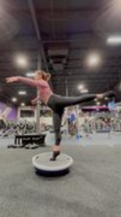 Woman Balances on One Leg on Balancing Ball While Stretching