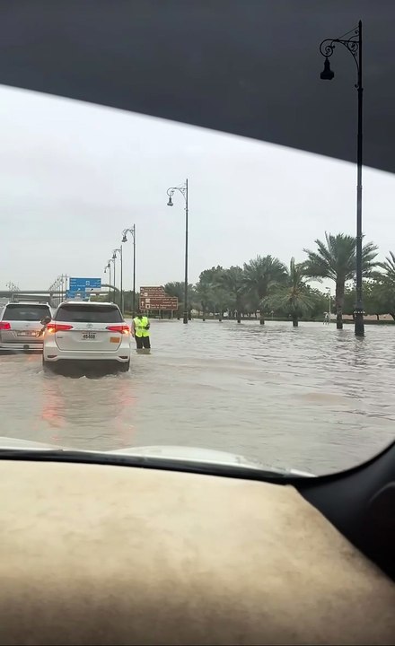Sharjah officer standing deep in murky floodwaters directing traffic