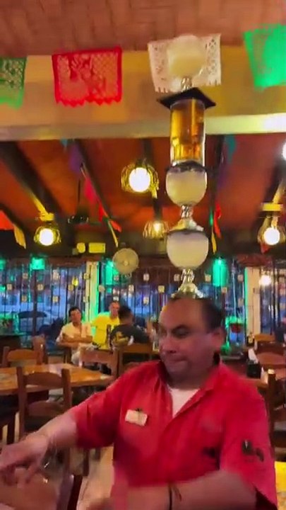 Un serveur apporte les boissons en équilibre sur sa tête