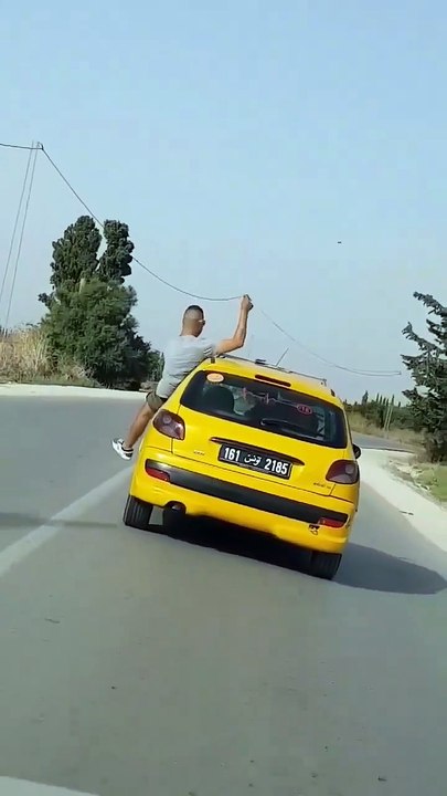 صاحب تكسي يخرج من نافذة سيارة و يقوم بحركات بهلوانية