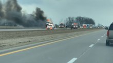 Woman spots smoke and flames as car hauler catches fire on the side of the road