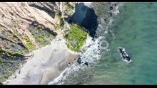 Aerial top view of ocean blue waves break on a beach.