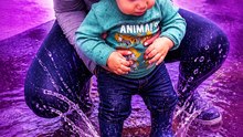 Mom assists her little boy in discovering his jumping potential in the rain