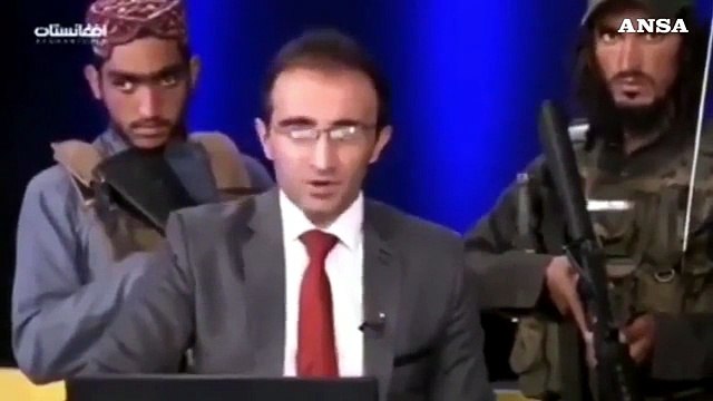 Afghanistan, anchor in studio tv con dietro i Talebani armati