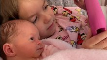 Charming newborn resisting sleep while connecting with her affectionate older sister