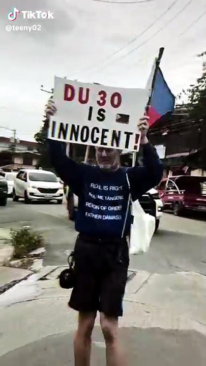 A foreigner in the Philippines waving a banner/poster that says 'Duterte is Innocent. [Full Movie]