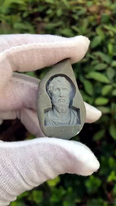 Il grave au laser un buste antique de guerrier barbu sur un caillou