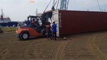 Unloading H-beams from the container by pulling them out with a forklift.