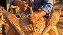 An old man carves a life-size Owl from wood.