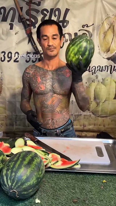 The watermelon cutting skills of a man with tattoos all over his body