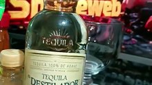 presentando una botella de tequila destilador y una bolsa de tostachos de la marca Barcel viernes