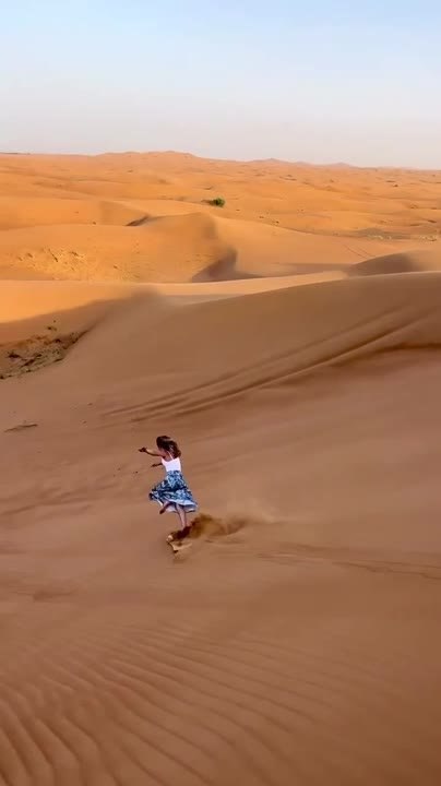 Woman Falls While Sand Boarding Down Tall Sand Dune