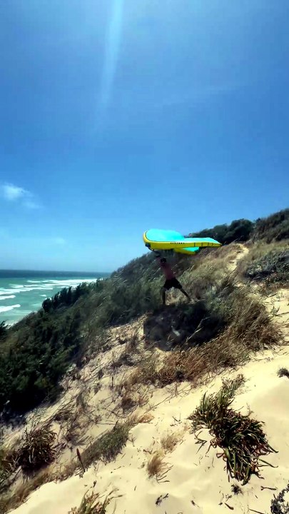 Un twin autrichien décolle au wingfoil, suspendu au-dessus dune de sable sans harnais
