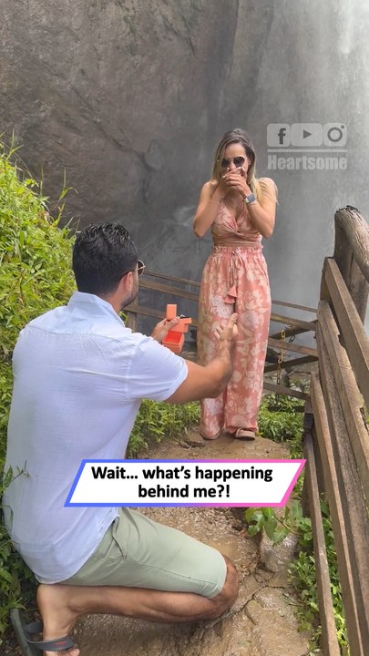 Surprise marriage proposal catches woman off guard while she admires a breathtaking waterfall scene