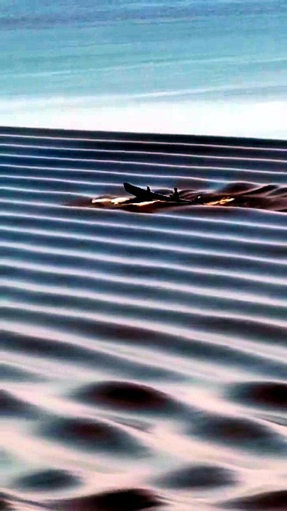 Un bateau au milieu de vagues qui ressemblent à des dunes de sable sur le fleuve Qiantang