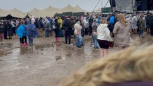 Festivalgoers Navigate Wind And Waterlogged Ground