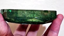 Fascinated ashtray in green and gold tones in epoxy resin